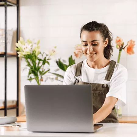 Young woman working on her small business on a laptop in a florist shop