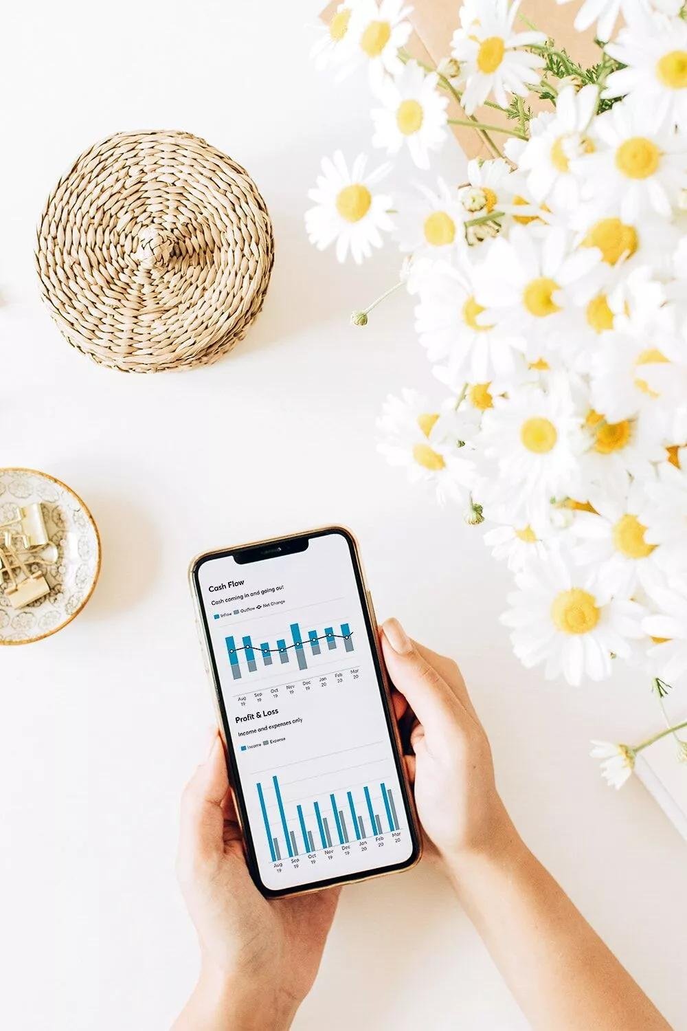 A woman holding a mobile phone using a budgeting app to track expenses